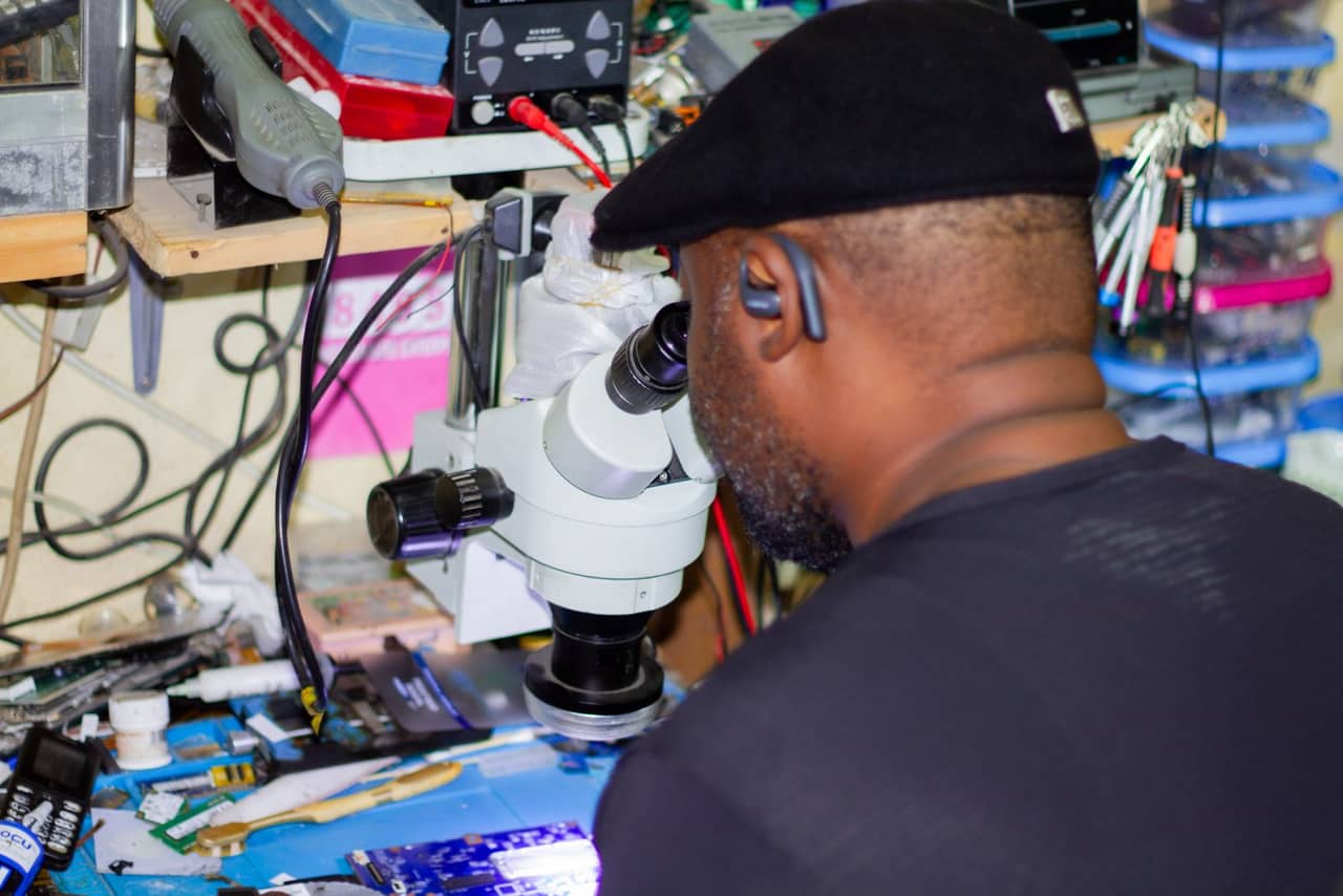 Furaha Mwambenja repairing a circuit board under a microscope